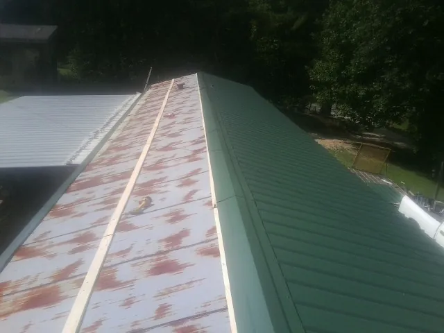 Old rusted panels beside newly installed green metal roofing — Wind Damage Roof Repair by Roofing Brothers in Montvale