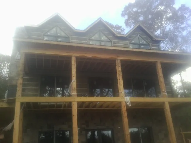 Dormers and porch framing on a large log home under construction — Roof Coating work by our crew in Montvale