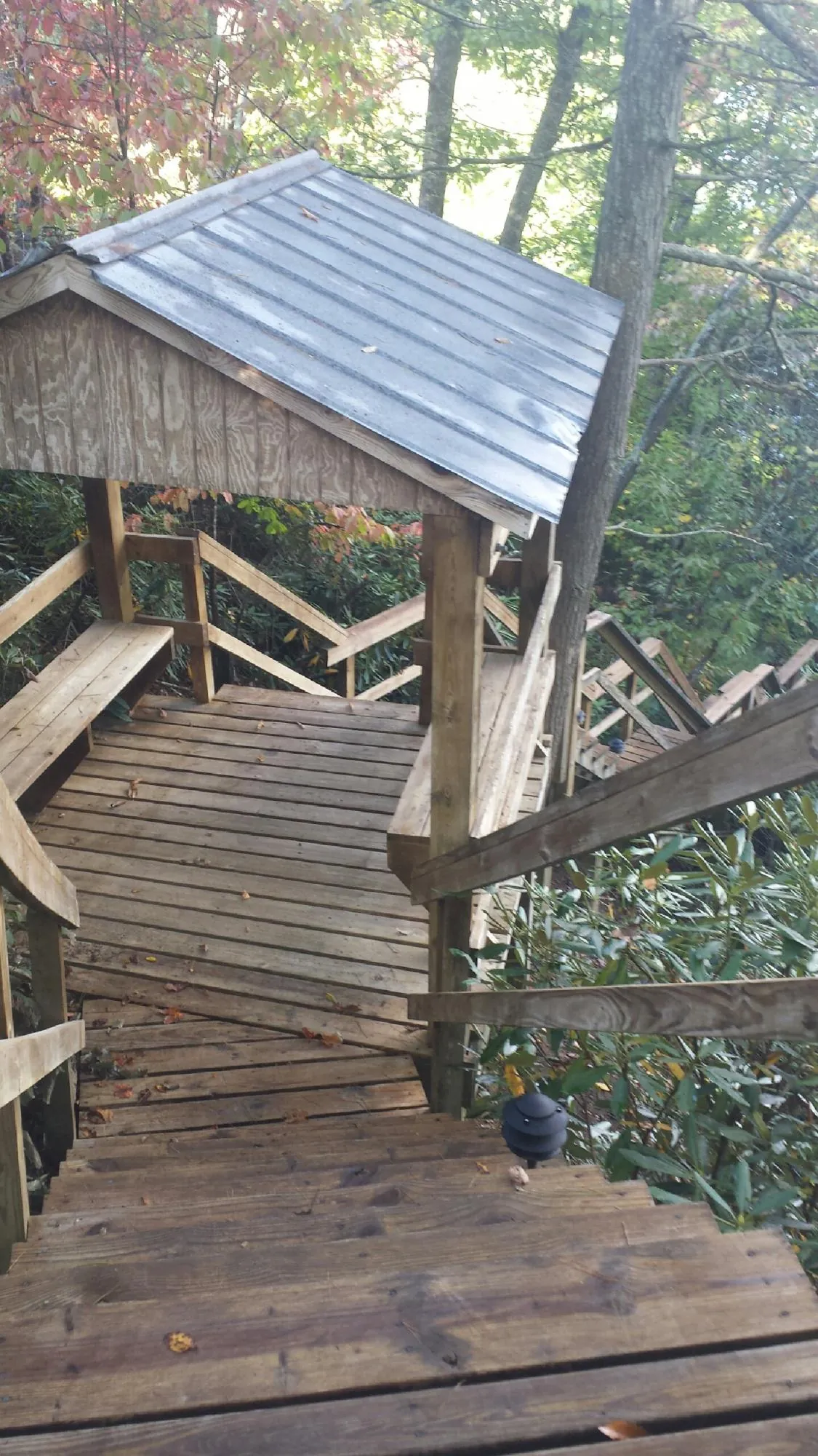 Metal roofed shelter over wooden steps on a wooded walkway — Skylight Repair & Installation work by our crew in Montvale